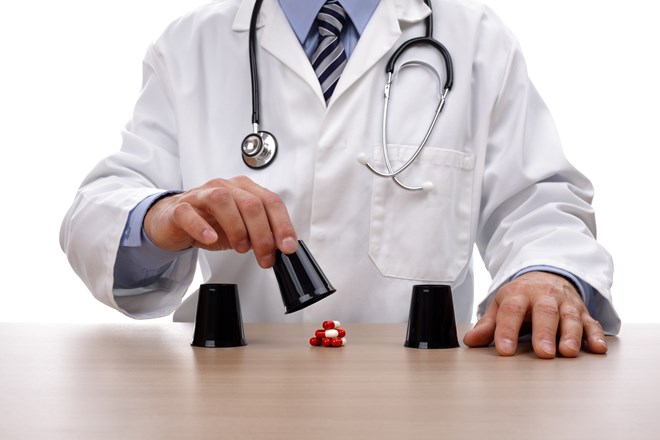 Doctor playing the classic shell game with cups and a pile of pills